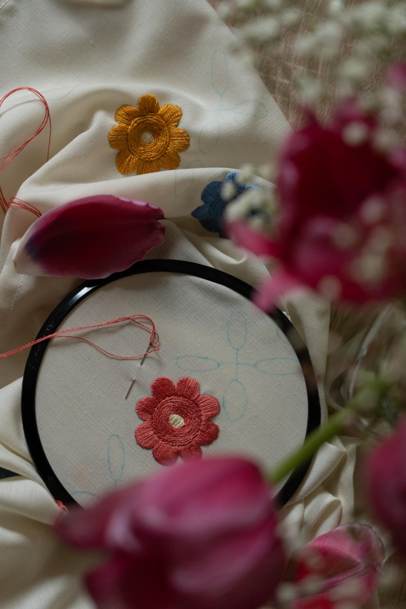 Close-up of hand embroidering floral motif on linen